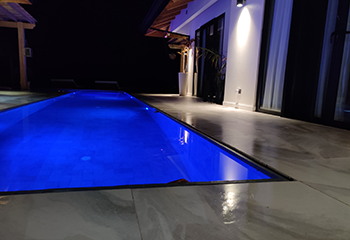 Contemporary infinity pool design featuring vanishing edges and nighttime illumination